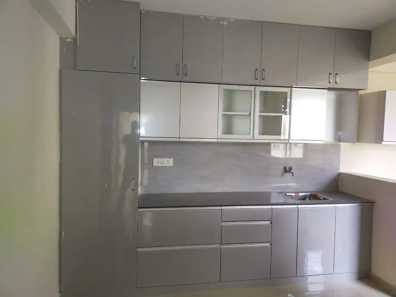 Finished grey modular kitchen with glass-shutter cabinets and granite counter