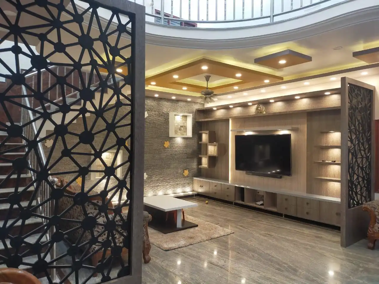 Double-height living room with jaali partition and custom TV media wall